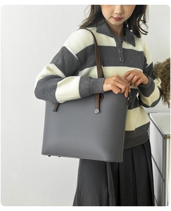 Detailed macro view of grey litchi texture leather tote with brown handle straps