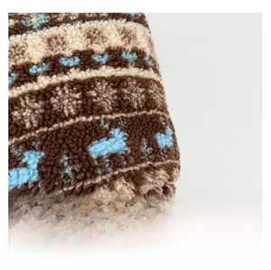Close-up of plush fleece fabric with Nordic elk and snowflake patterns in warm tones
