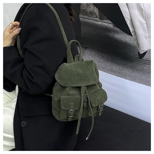 Detail of dark green matte suede backpack featuring drawstring closure and metal buckles