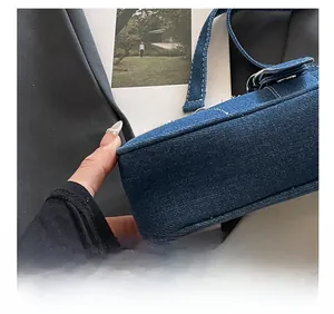 Gros plan détaillé du sac en jean bleu montrant les surpiqûres et la boucle en métal
