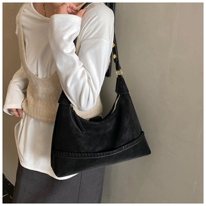 Detail of black suede hobo bag featuring woven stitching and gold zipper closure