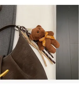 Detailed view of brown plush bear charm with Love ribbon on lychee grain leather bag
