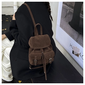 Detail of dark brown suede mini backpack with double front pockets on a model back
