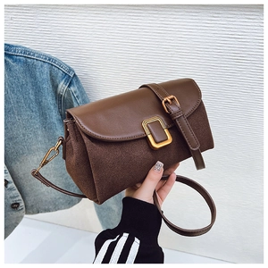 Close-up of a vintage dark brown leather shoulder bag with a gold rectangular metal buckle
