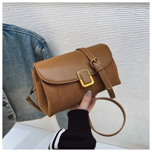 Detail of caramel brown crossbody bag with gold buckle and smooth leather patchwork