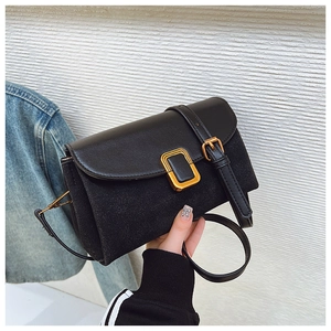Close-up of black crossbody bag with mixed suede and leather textures and gold buckle