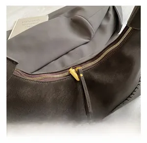 Detailed macro of golden zipper and woven seam on textured dark grey pillow bag
