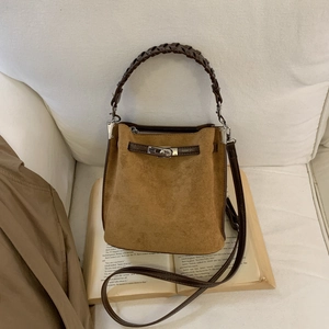 Braune Wildleder Beuteltasche mit Flechtgriff und Silberverschluss auf Sofa