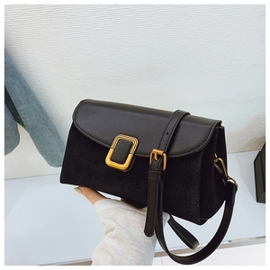 Detail of black crossbody bag featuring suede texture and gold rectangular metal buckle