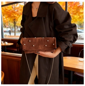Detail of brown faux suede bag with silver studs and chain strap in autumn setting