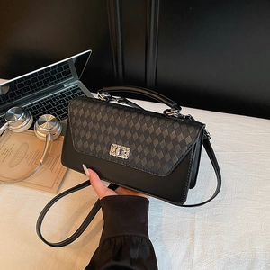Classic black quilted crossbody bag with metal rotary lock on a minimalist desk