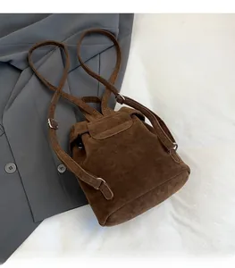 Top view of a dark brown suede mini backpack featuring a flap cover and slender straps