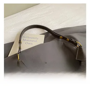 Detail of adjustable leather strap with gold metal rivets on a brown hobo pillow bag