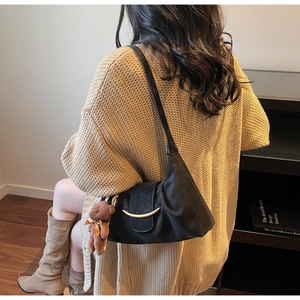 Chic black minimalist hobo shoulder bag featuring a golden buckle and plush bear pendant