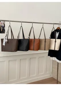 Five assorted large tote bags in neutral tones hanging on a minimalist metal rack display