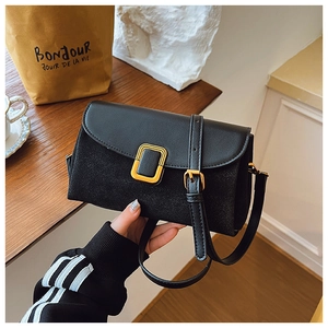 Close-up of black crossbody bag with gold buckle and textured patchwork material