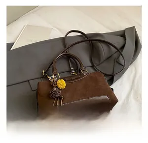 Détail du sac à main marron foncé en daim avec nœud décoratif et pompons doux