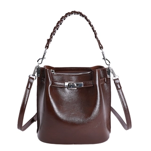 Dunkelbraune Lackleder-Eimertasche mit geflochtenem Griff und Silberschnalle auf Weiß