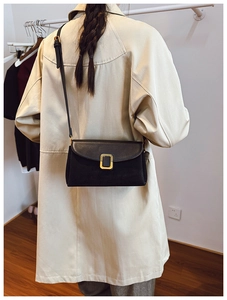 Rear view of model wearing a minimalist black leather crossbody bag with gold metal buckle