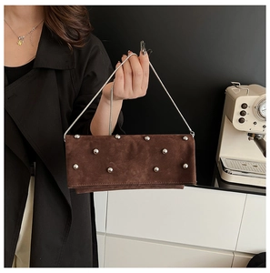 Detail of retro dark brown suede crossbody bag with silver studs and chain strap