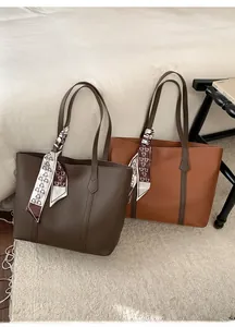 Detailed view of brown leather tote bags with decorative printed scarves on soft carpet