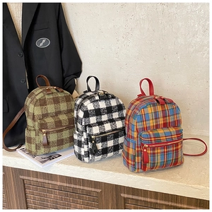 Detailed view of plaid tweed backpacks in green, black, and multicolor textured fabric