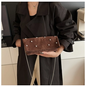 Detail of brown suede crossbody bag with silver stud matrix and elegant metal chain