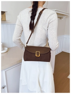 Detail view of a brown vintage leather shoulder bag with gold buckle and adjustable strap