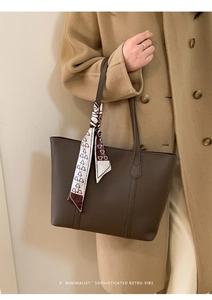 Detail of a brown tote bag with bear print silk scarf accent and matte leather finish