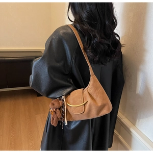 Detail of caramel faux leather bag with crescent metal clasp and brown teddy bear charm