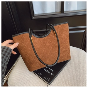 Detail of vintage brown suede tote bag with diamond quilting and black leather trim