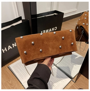 Detailed view of brown suede shoulder bag with silver rivets and metal chain strap