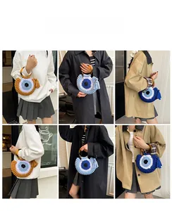 Détail d'un sac en maille avec motif œil grec, poignée en résine et pompons bohèmes