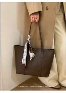 Detail of a brown leather tote bag featuring a printed silk scarf with bear patterns