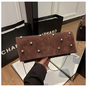 Close-up of vintage brown suede shoulder bag with silver stud rivets and chain strap