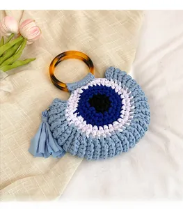 Détail du sac en tricot fait main Evil Eye avec poignée ambrée et pompon décoratif bleu