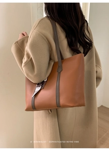 Close-up of brown textured leather tote bag with printed silk scarf and grey strap detail