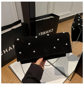 Detail of black suede bag with silver metallic rivets and slim chain shoulder strap