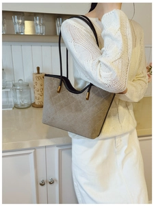 Detail of taupe quilted suede tote bag with elegant gold hardware on a shoulder strap
