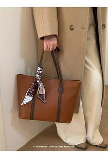Detail of caramel tote bag featuring decorative bear print scarf and dual-tone shoulder straps