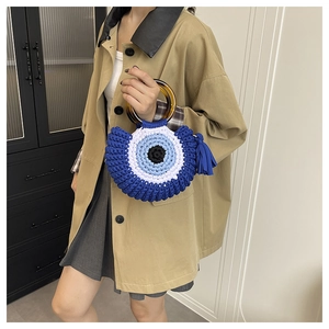 Détail d'un sac en maille tissé main avec motif œil bleu et anse en résine