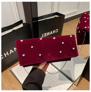 Close-up of burgundy velvet envelope clutch featuring silver rivets and chain strap