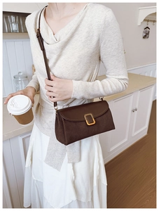 Close-up of a brown leather shoulder bag with a vintage square gold clasp on the flap