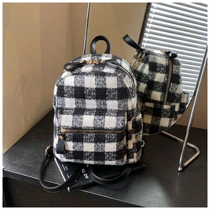 Detail view of mini plaid plush backpack with gold zippers and black leather straps