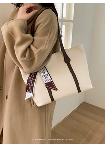 Detail of off-white tote bag featuring a decorative silk scarf and deep brown handle