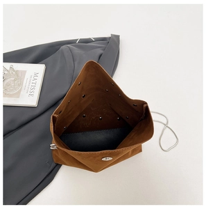 Detail view of brown suede handbag interior with silver magnetic closure and metal eyelets