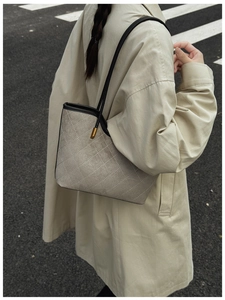Detail of grey suede shoulder bag with diamond stitching and gold hardware on model