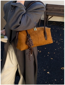 Détail du sac Boston en daim marron avec pendentif chocolat et double fermeture éclair