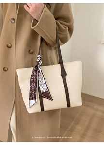Detail of cream tote bag with contrast brown straps and decorative bear print scarf handle