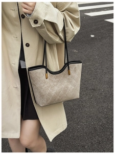 Detailed macro view of beige quilted suede tote bag with black trim and wavy edge detail